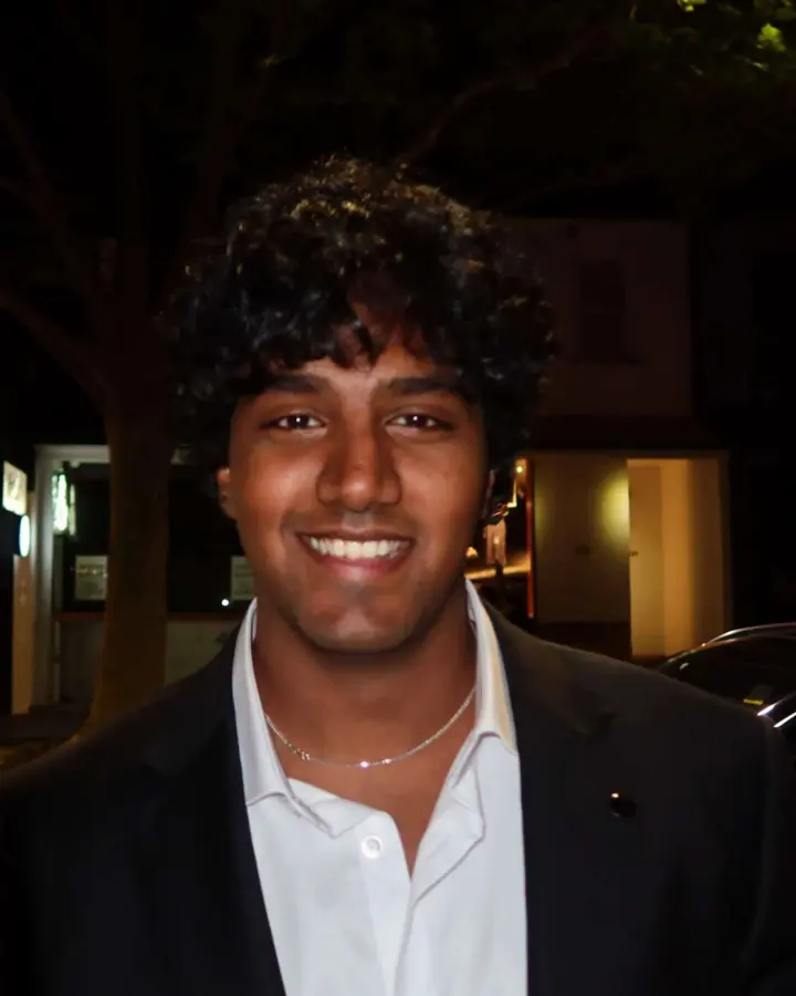 Manindra de Mel smiling at night in a black blazer and white shirt